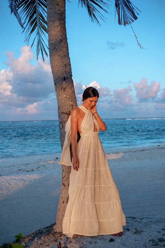 Woman wearing the sand Esmeralda Maxi Dress on the beach by the sea