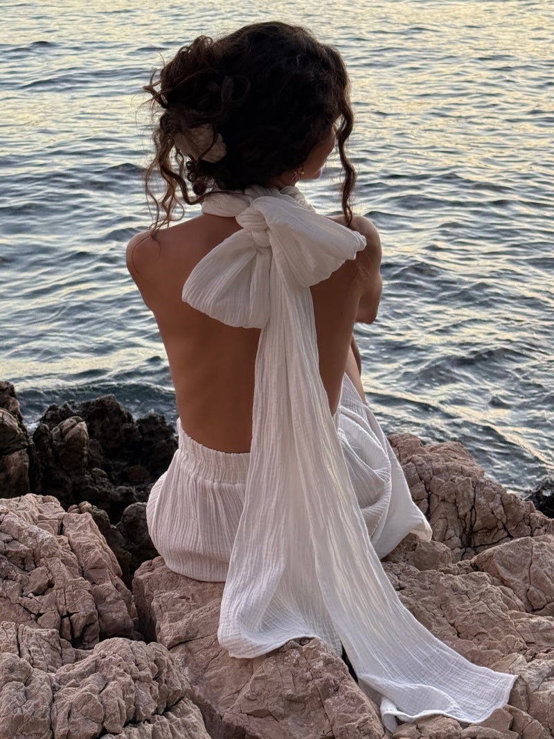 Back view of a white Boheme by Ena convertible dress with a tied halter neckline by the sea