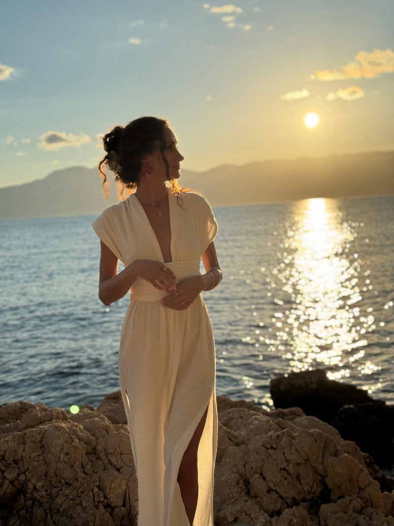 Woman wearing a white Boheme by Ena convertible dress by the sea at sunset