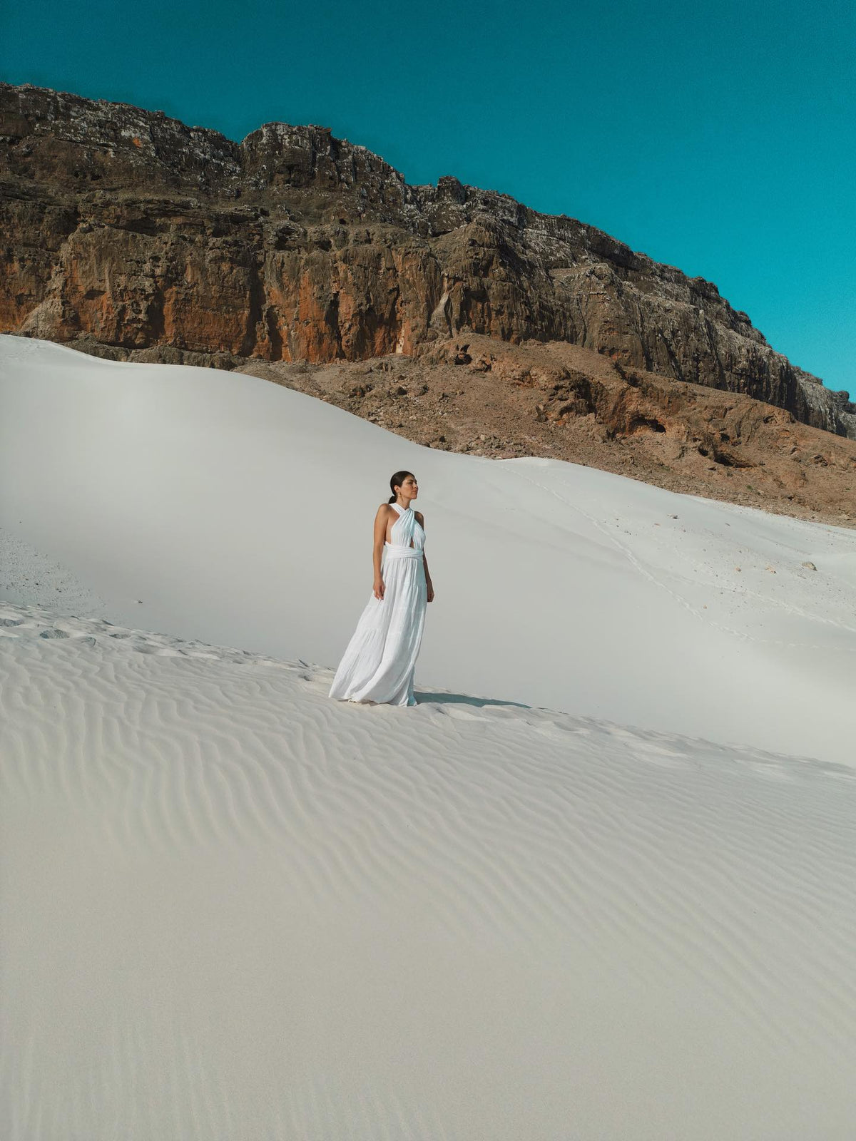 Woman wearing a white Bohème by Ena maxi dress in the sand dunes