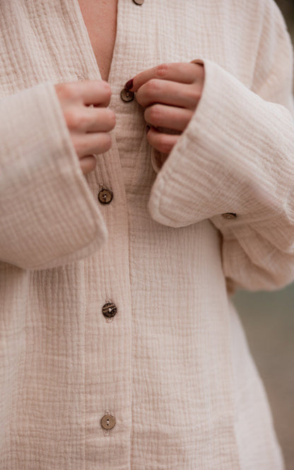 Close-up of textured organic cotton fabric and natural coconut buttons on the sand Coconut shirt