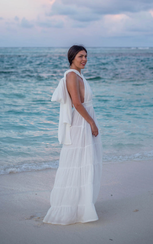 Woman wearing the white Esmeralda Versatile Maxi Dress by Bohème by Ena on the beach