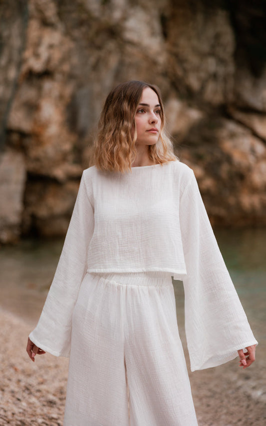 Woman wearing the white Oasis matching set with a relaxed top and flowing wide sleeves